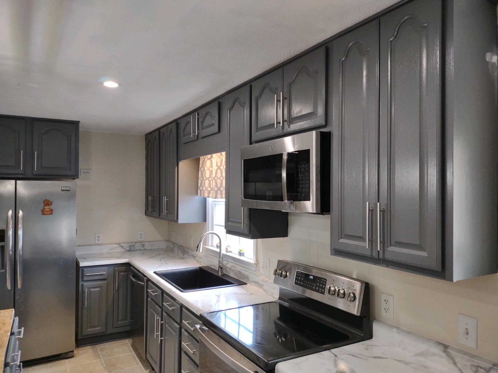 Modern kitchen with gray cabinets, stainless steel appliances, marble countertops, and a window above the sink—perfect for your next home remodeling project.